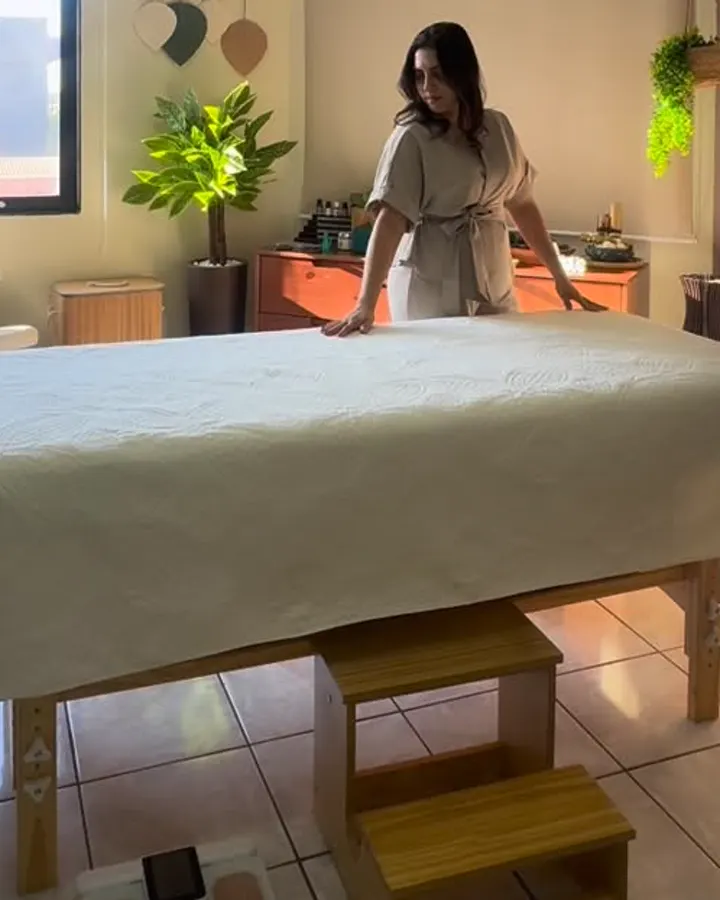 Sala de massagem com maca, plantas e luz natural
