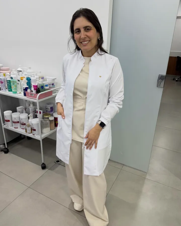 Janaína de jaleco branco ao lado do carrinho de produtos para a pele