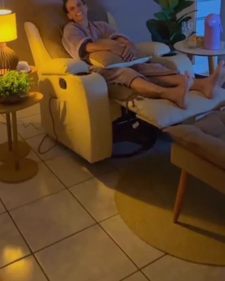 Cliente relaxando em poltrona reclinável sob luz quente de abajur